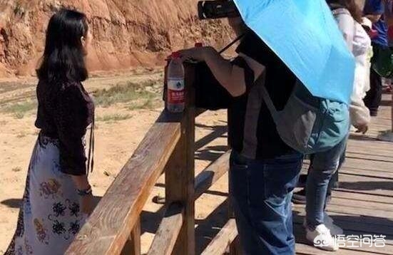 男子丹霞景区翻护栏，游客翻越护栏脚踩丹霞地貌拍照